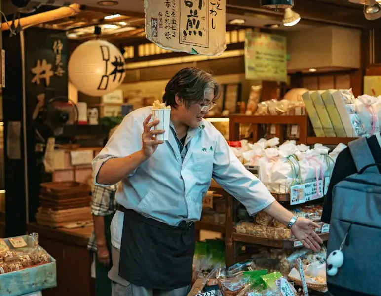 A shopkeeper serving at the counter of a small snack shop